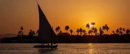 مركب شراعي عند غروب الشمس على نهر النيل في مصر