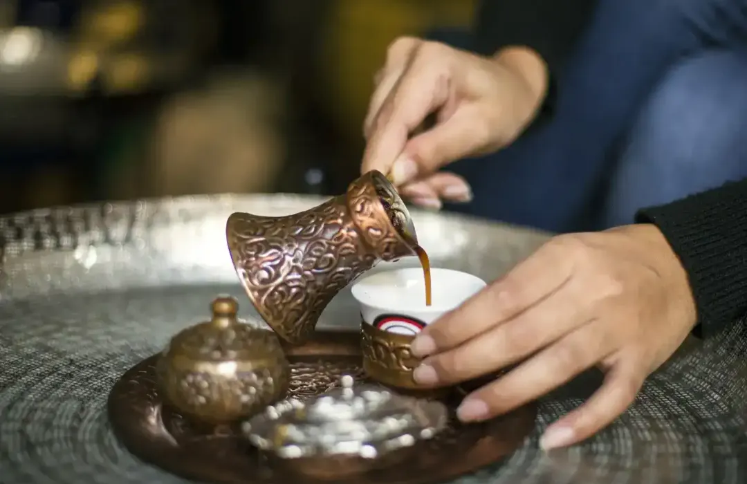 Close-up of hand pouring Egyptian coffee in Antique Coffee Set