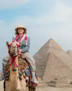 Woman riding a camel in front of the Great Pyramid of Giza